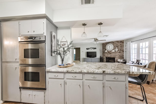 1721 Bowline Rd, Houston, TX 77062 - kitchen with stainless steel double oven, a ceiling fan, open floor plan, a brick fireplace, and light stone counters