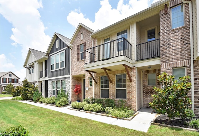 9428 Caddo Ridge Ln, Cypress, TX 77433 - townhome / multi-family property with a balcony, board and batten siding, brick siding, and a front lawn