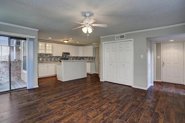 2300 Old Spanish Trl Unit 1128, Houston, TX 77054 - kitchen featuring ceiling fan, crown molding, dark wood-type flooring, decorative backsplash, and white cabinetry