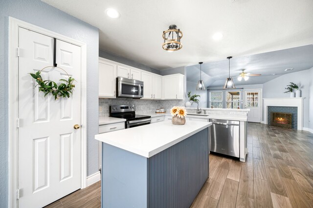 9710 Golden Park Ln, Houston, TX 77088 - kitchen featuring stainless steel appliances, a peninsula, white cabinetry, a ceiling fan, and wood finished floors