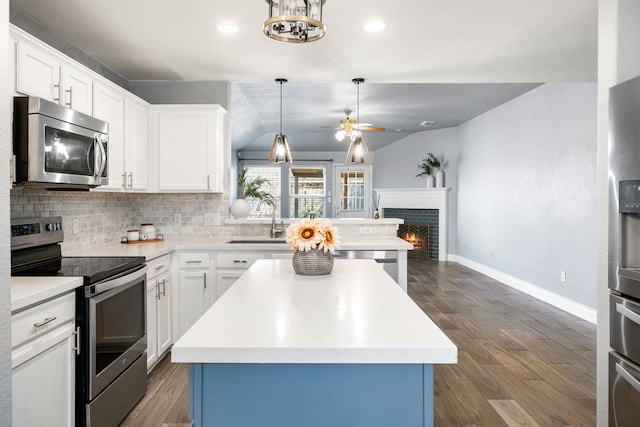 9710 Golden Park Ln, Houston, TX 77088 - kitchen featuring appliances with stainless steel finishes, a ceiling fan, vaulted ceiling, light countertops, and a warm lit fireplace