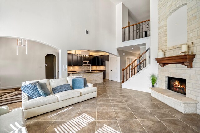 16206 Lakewood Field Dr, Tomball, TX 77377 - tiled living room featuring arched walkways, a towering ceiling, stairway, and a fireplace