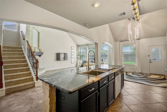 16206 Lakewood Field Dr, Tomball, TX 77377 - kitchen featuring arched walkways, dark cabinets, an island with sink, vaulted ceiling, and open floor plan