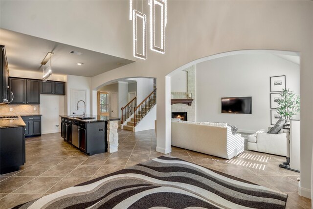 16206 Lakewood Field Dr, Tomball, TX 77377 - living area featuring a brick fireplace, arched walkways, tile patterned flooring, and a towering ceiling