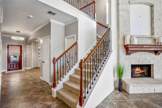 16206 Lakewood Field Dr, Tomball, TX 77377 - entrance foyer with a stone fireplace, arched walkways, ornamental molding, stairs, and dark tile patterned floors