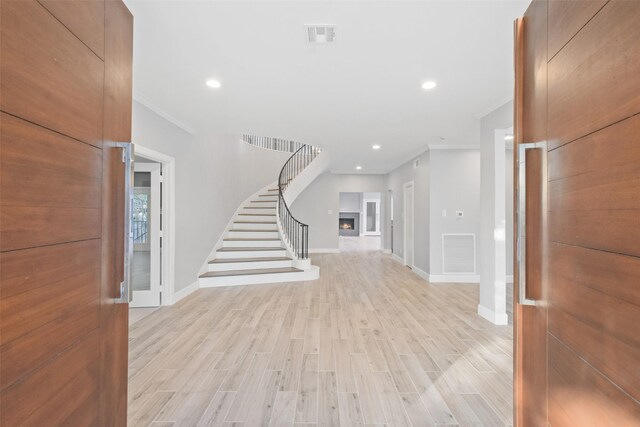 5110 Contour Pl, Houston, TX 77096 - foyer entrance featuring stairs, light wood-style flooring, recessed lighting, a warm lit fireplace, and ornamental molding
