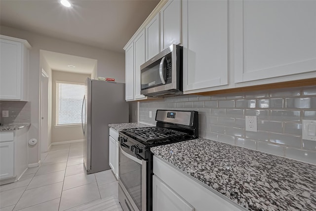 29626 Weber Way Ct, Katy, TX 77494 - kitchen with stainless steel appliances, dark stone counters, white cabinetry, and light tile patterned floors