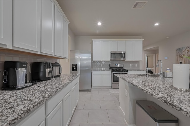 29626 Weber Way Ct, Katy, TX 77494 - kitchen featuring appliances with stainless steel finishes, tasteful backsplash, white cabinets, light stone countertops, and light tile patterned flooring