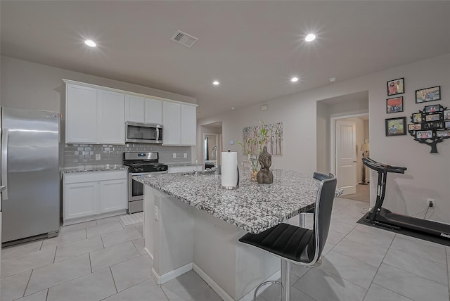 29626 Weber Way Ct, Katy, TX 77494 - kitchen with appliances with stainless steel finishes, light stone counters, white cabinets, a breakfast bar, and recessed lighting