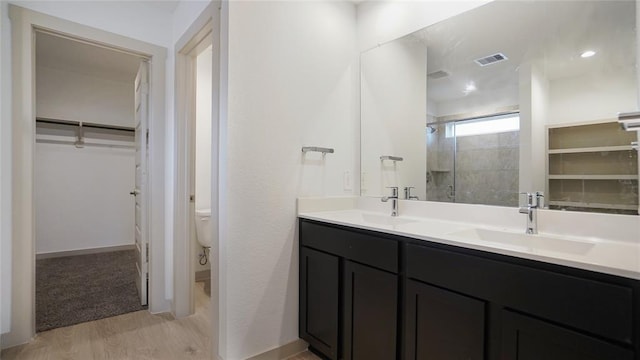 30106 Reagans Ranch Dr, Katy, TX 77494 - bathroom featuring double vanity, a spacious closet, tiled shower, and wood finished floors