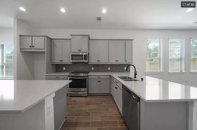 120 Lukewood Cir, Conroe, TX 77318 - kitchen with appliances with stainless steel finishes, gray cabinetry, a peninsula, light countertops, and decorative backsplash