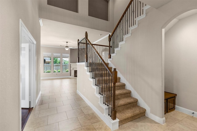28647 Maple Red Dr, Katy, TX 77494 - staircase with ceiling fan, a fireplace, crown molding, tile patterned floors, and arched walkways