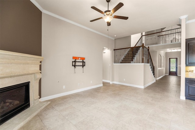 28647 Maple Red Dr, Katy, TX 77494 - unfurnished living room with ceiling fan, stairway, crown molding, a fireplace, and a towering ceiling