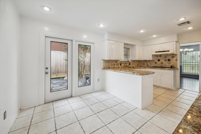 2415 W T C Jester Blvd, Houston, TX 77008 - kitchen featuring under cabinet range hood, backsplash, a peninsula, light stone countertops, and white cabinets