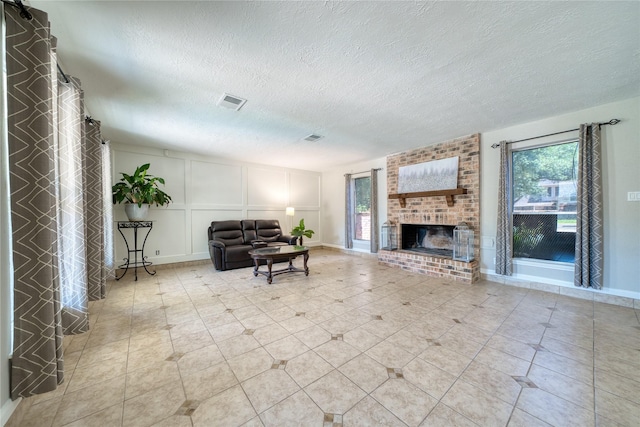 21434 Park Bluff Dr, Katy, TX 77450 - living area featuring healthy amount of natural light, a textured ceiling, a brick fireplace, a decorative wall, and light tile patterned flooring