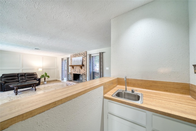 21434 Park Bluff Dr, Katy, TX 77450 - kitchen with wood counters, open floor plan, a textured ceiling, a fireplace, and a textured wall