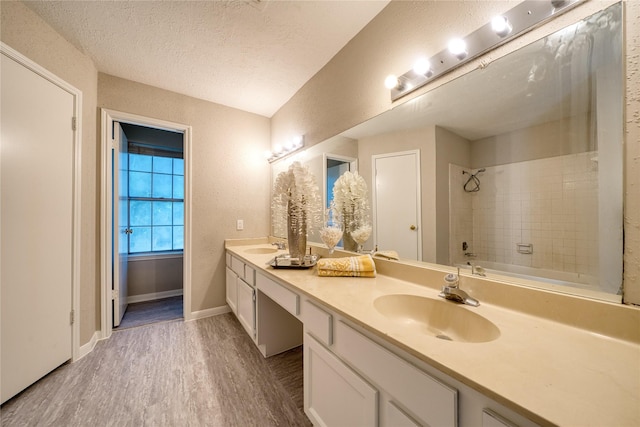 21434 Park Bluff Dr, Katy, TX 77450 - full bathroom with double vanity, wood finished floors, a textured ceiling, and washtub / shower combination