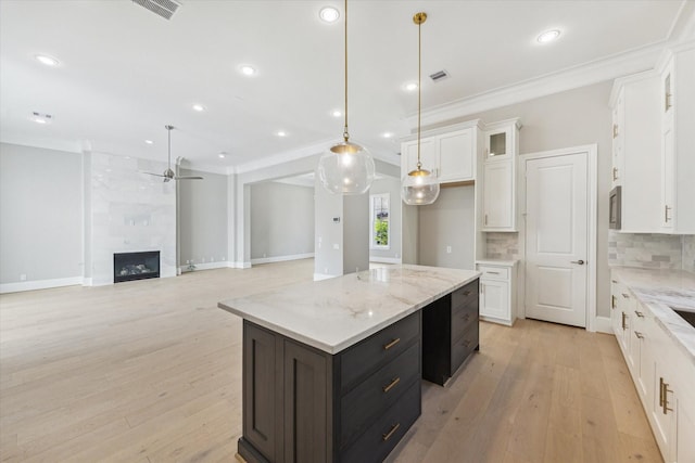 7515 Little Caprese Ln, Houston, TX 77055 - kitchen with white cabinets, crown molding, a kitchen island, a ceiling fan, and glass insert cabinets