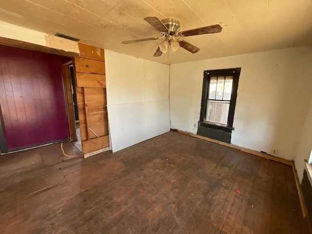 115 E Hallie St, Floydada, TX 79235 - spare room featuring a ceiling fan, hardwood / wood-style flooring, and wooden walls