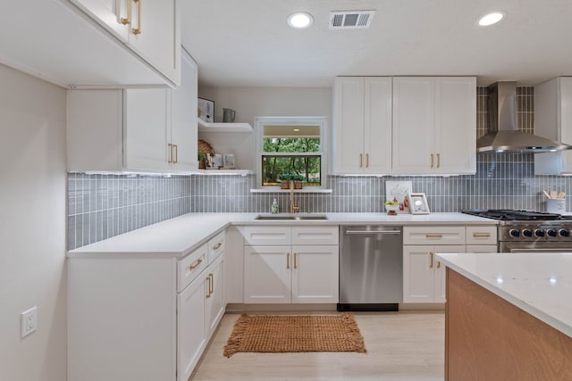 10813 Colony Wood Pl, The Woodlands, TX 77380 - kitchen with appliances with stainless steel finishes, wall chimney exhaust hood, light wood-style floors, light countertops, and white cabinetry