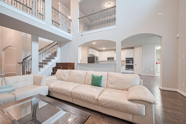 11810 White Flint Ln, Cypress, TX 77433 - living room with arched walkways, a towering ceiling, stairs, and dark wood finished floors