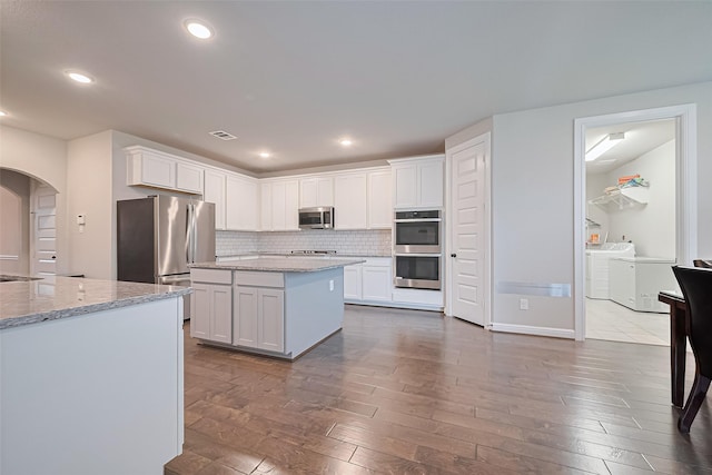11810 White Flint Ln, Cypress, TX 77433 - kitchen with stainless steel appliances, washer and clothes dryer, arched walkways, dark wood finished floors, and white cabinets