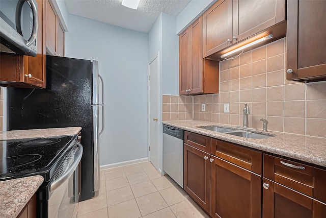 7900 N Stadium Dr Unit 123, Houston, TX 77030 - kitchen featuring appliances with stainless steel finishes, decorative backsplash, a textured ceiling, light tile patterned floors, and light stone countertops