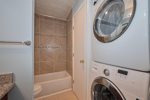 7900 N Stadium Dr Unit 123, Houston, TX 77030 - laundry area featuring stacked washer / dryer, light tile patterned floors, and a textured ceiling