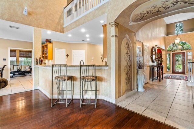 7914 Chianti Ct, Sugar Land, TX 77479 - kitchen featuring a towering ceiling, wood finished floors, arched walkways, healthy amount of natural light, and a kitchen breakfast bar