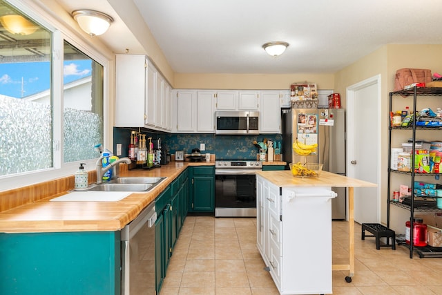 735 Red Rock Canyon Dr, Katy, TX 77450 - kitchen with appliances with stainless steel finishes, wood counters, white cabinets, light tile patterned flooring, and backsplash