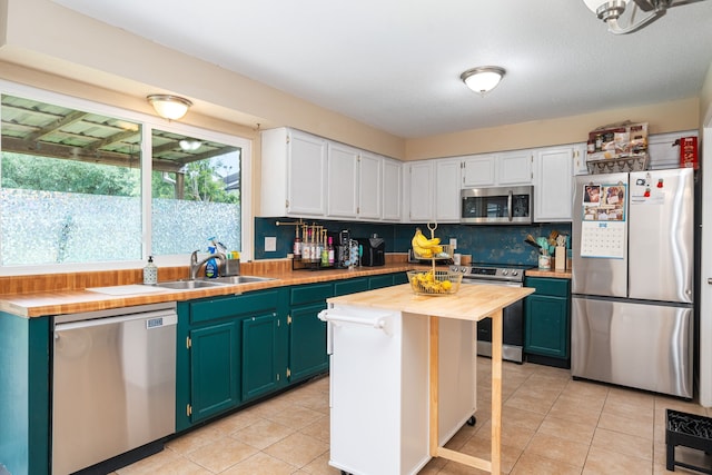 735 Red Rock Canyon Dr, Katy, TX 77450 - kitchen with stainless steel appliances, wood counters, decorative backsplash, white cabinetry, and light tile patterned floors