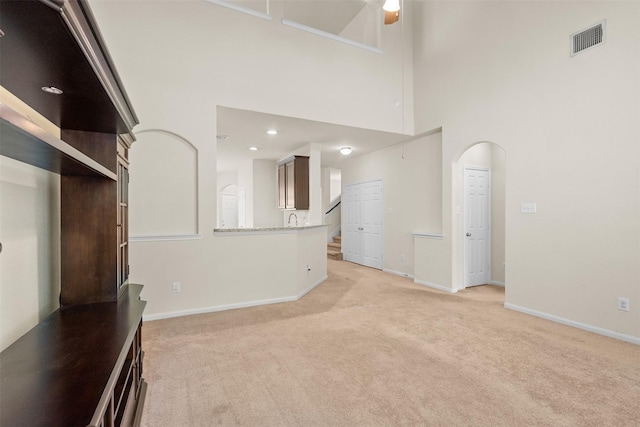 6439 Wilshire Rdg, Houston, TX 77040 - unfurnished living room featuring light carpet, a towering ceiling, and arched walkways