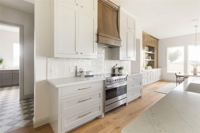 1355 Bluebonnet Ridge Dr, Chappell Hill, TX 77426 - kitchen featuring stainless steel electric stove, custom range hood, decorative backsplash, light floors, and decorative light fixtures