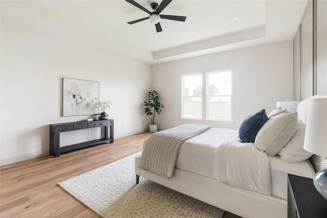 1355 Bluebonnet Ridge Dr, Chappell Hill, TX 77426 - bedroom featuring light wood finished floors, a tray ceiling, and a ceiling fan