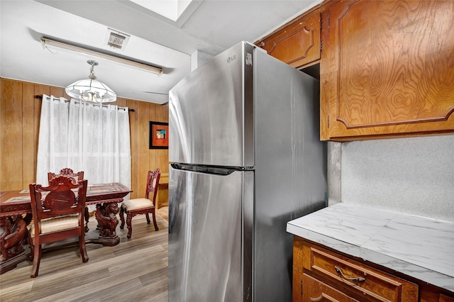 4007 Wedgewood St, Houston, TX 77093 - kitchen with freestanding refrigerator, a chandelier, brown cabinets, wood walls, and light wood-style flooring