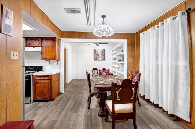4007 Wedgewood St, Houston, TX 77093 - dining room featuring ceiling fan, a chandelier, built in features, wood walls, and wood finished floors