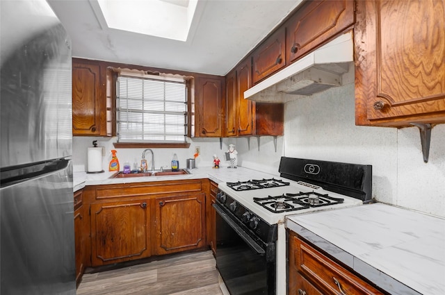 4007 Wedgewood St, Houston, TX 77093 - kitchen with white gas range oven, freestanding refrigerator, under cabinet range hood, light countertops, and wood finished floors