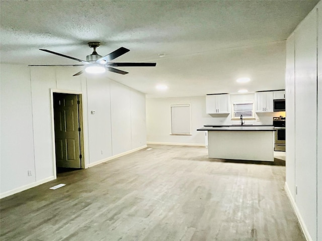 17909 Pine St Unit A, Crosby, TX 77532 - unfurnished living room with light wood-style floors, a textured ceiling, and a ceiling fan