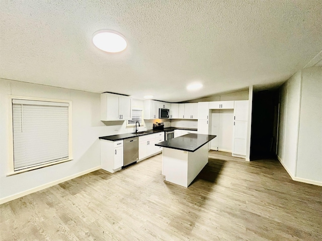 17909 Pine St Unit A, Crosby, TX 77532 - kitchen with stainless steel appliances, a textured ceiling, light wood-type flooring, a center island, and dark countertops