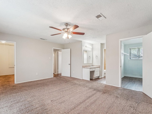 4901 Ripple Creek Dr, Baytown, TX 77521 - unfurnished bedroom with carpet, a spacious closet, a closet, ensuite bathroom, and a textured ceiling
