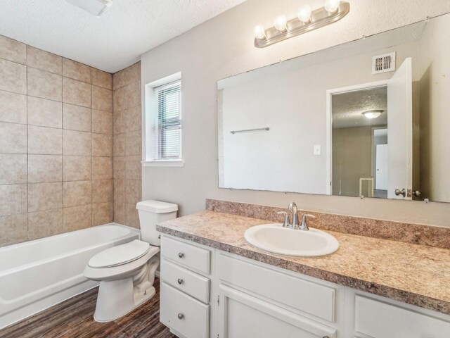 4901 Ripple Creek Dr, Baytown, TX 77521 - bathroom featuring a textured ceiling, vanity, wood finished floors, and shower / tub combination