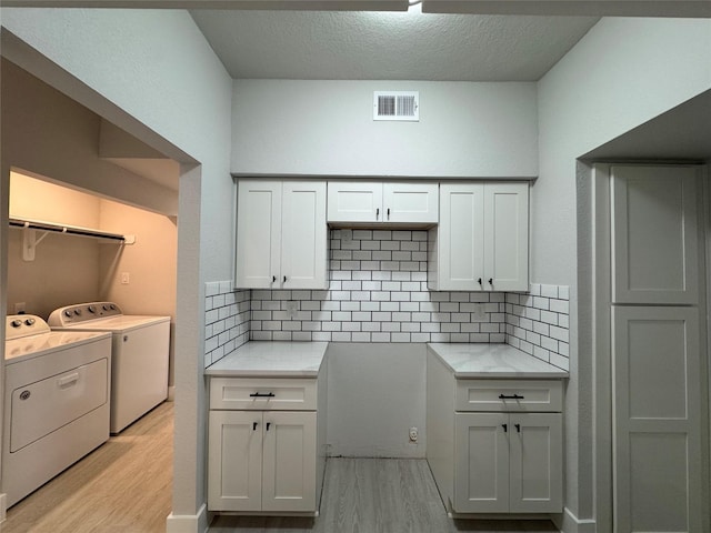 9803 Club Creek Dr Unit 134, Houston, TX 77036 - kitchen with independent washer and dryer, light wood-style flooring, backsplash, and a textured ceiling