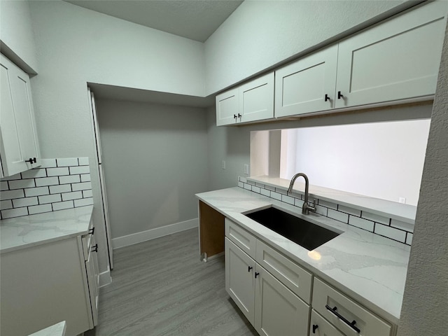 9803 Club Creek Dr Unit 134, Houston, TX 77036 - kitchen with tasteful backsplash, light stone counters, light wood finished floors, and white cabinets