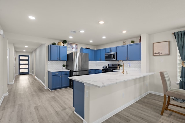 10433 Russell Pines Dr, Rosharon, TX 77583 - kitchen featuring stainless steel appliances, a peninsula, blue cabinetry, light wood finished floors, and decorative backsplash