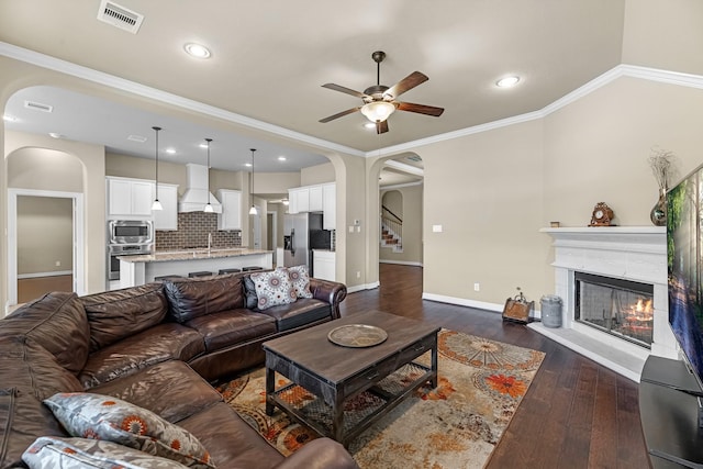 5622 Chipstone Trail Ln, Katy, TX 77493 - living area with arched walkways, a ceiling fan, dark wood-style floors, a tile fireplace, and crown molding