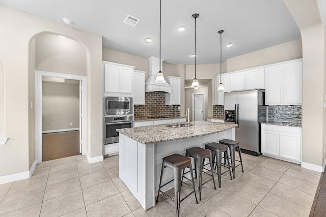 5622 Chipstone Trail Ln, Katy, TX 77493 - kitchen featuring appliances with stainless steel finishes, a center island with sink, decorative backsplash, a kitchen bar, and light stone counters