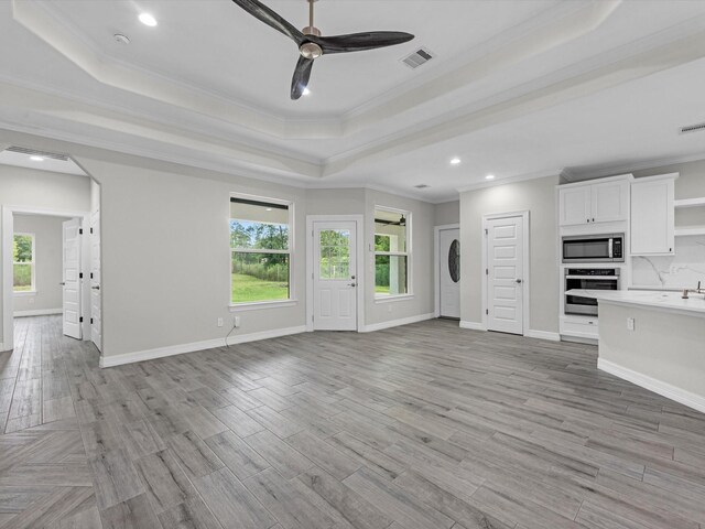 14606 Half Circle St, Splendora, TX 77372 - unfurnished living room with a tray ceiling, ornamental molding, plenty of natural light, a ceiling fan, and stacked washing machine and dryer