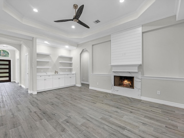14606 Half Circle St, Splendora, TX 77372 - unfurnished living room featuring arched walkways, a raised ceiling, a ceiling fan, a fireplace, and ornamental molding