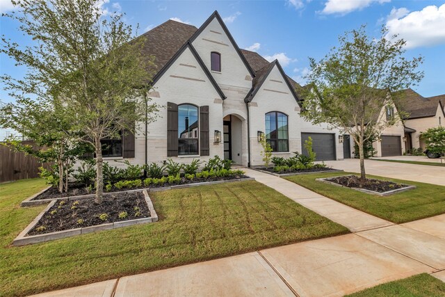 6826 Mirabeau Ln, Katy, TX 77493 - french country style house featuring driveway, an attached garage, brick siding, and a shingled roof