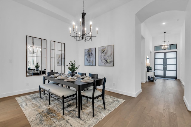 6826 Mirabeau Ln, Katy, TX 77493 - dining area with a chandelier, arched walkways, a towering ceiling, wood finished floors, and french doors